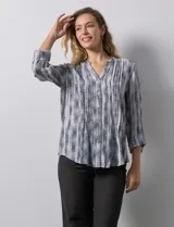 Blusa de gasa estampada con cuello a la base, escote en V y abertura central con botones. Delantera con plisados y mangas 3/4 regulables con presilla y botón.