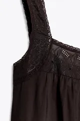 Vestido midi color marrón oscuro, con tirantes anchos y escote recto. Presenta detalle de puntilla en el escote y bordados a tono en el ruedo.