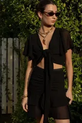 Top negro con escote en V, mangas cortas amplias y lazo central ajustable.