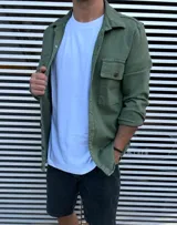 Sobre camisa verde militar de manga larga con cuello clásico, cierre frontal con botones y dos bolsillos con solapa en el pecho.