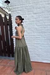 Vestido largo verde oliva de tela simil agamuzada, con escote halter, espalda baja y volados en cuello y cadera.