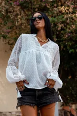 Camisa blanca de plumetí con cuello mao, mangas largas abullonadas con puños elásticos y cordón con borlas en el escote.