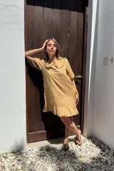 Vestido corto color beige de voile de rayon, con cuello bebé con volados y mangas cortas abullonadas.