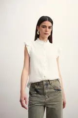 Camisa color amarillo pálido con cuello mao, sin mangas, con volados en los hombros y en el frente.