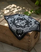 Pañuelo cuadrado negro con estampado de anclas, rayos, estrellas y texto en blanco.