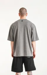 Remera gris melange de corte crop y calce oversize, con hombros caídos, cuello redondo y doble costura.