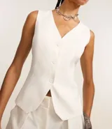 Chaleco de vestir color blanco hueso, con escote en V, cierre frontal con botones y espalda abierta. Corte sastrero.