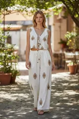 Conjunto de pantalón y chaleco blancos con bordados rojos. El chaleco es corto, con escote en V y se ata en el frente. El pantalón es recto y de tiro alto.