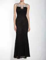 Vestido largo de fiesta negro con encaje y cuello redondo con detalle de pedrería. Sin mangas, corte sirena y espalda descubierta.