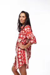 Vestido corto tipo camisero con botones al frente y mangas cortas con elástico y volado. Estampado con flores rojas y beige.