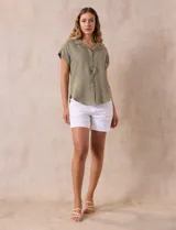 Camisa verde oliva de manga corta con cuello con solapa y abertura central con botones. Tiene un bolsillo aplicado en el pecho.