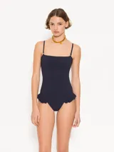 Traje de baño entero color azul marino con escote recto y breteles desmontables. Presenta volados en la cadera.