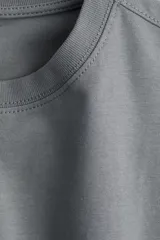 Remera gris de corte cuadrado y holgado, con cuello redondo y mangas cortas anchas. Confeccionada en tejido de punto suave de algodón.