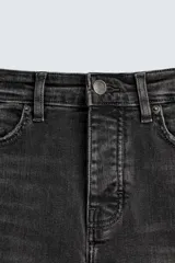 Pantalón de jean negro ajustado al cuerpo desde la cintura hasta el tobillo, de tiro medio y tejido elástico. Diseño de cinco bolsillos con lavado efecto roto y cierre frontal con cremallera y botón.