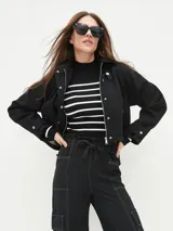 Campera corta negra con cierre frontal y cuello clásico.