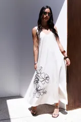 Vestido largo de tirantes color azul con estampado floral blanco en el lateral inferior.