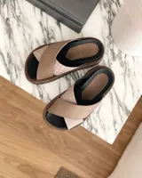 Sandalias Lucy de cuero color beige con tiras cruzadas y suela plana.