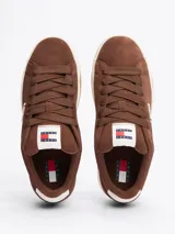 Zapatillas Tommy Jeans de corte bajo, color marrón, confeccionadas en gamuza con interior de poliéster y suela de goma. Presentan cordones, entresuela texturizada, etiqueta de la marca en el lateral y parche en la lengüeta.