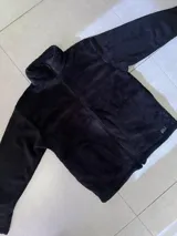 Buzo negro de poliéster con textura de sherpa y cierre frontal.