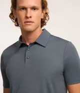 Camisa polo gris con cuello inglés abotonado y mangas cortas. Confeccionada en tejido de poliamida y elastano con tecnología Performance que proporciona mayor comodidad térmica, elasticidad y secado rápido.