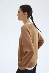 Buzo de punto fino color camel, de corte holgado con escote redondo y mangas raglán. Presenta cuello, puños y bajo acanalados.