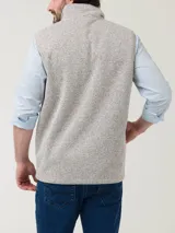 Chaleco de polar color beige jaspeado, con cuello alto y cierre frontal. Tiene tres bolsillos frontales con cierre.