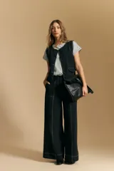 Pantalón ancho de tiro alto, color negro, con costuras contrastantes en blanco que definen los bolsillos y los bordes.