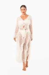 Vestido playero largo con estampado floral en tonos verdes y blancos, con volados de encaje en escote, mangas y ruedo. Mangas largas, abertura frontal con lazos para cerrar y aberturas laterales.