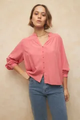 Camisa de manga larga color celeste, con cuello mao, escote en V y botones forrados, con puños elásticos.