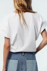 Camiseta blanca de algodón con cuello redondo, manga corta y bolsillo de plastrón en el delantero.