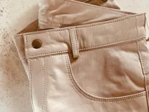 Pantalón de cuero ovino italiano color nude, corte mom fit con tiro semi alto y tajos inferiores.