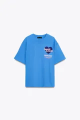 Camiseta celeste de algodón con corte oversize, cuello redondo, manga corta con hombro caído y estampado frontal con texto 'Taquería La Bonita' y un corazón.