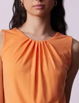 Blusa sin mangas color amarillo, con cuello redondo con frunces delanteros y abertura con botón en la espalda.