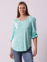 Blusa estampada color beige con cuello redondo calado y mangas 3/4 abullonadas con terminación elastizada.