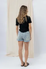 Short de jean azul claro con ruedo doblado fijo, tiro medio, calce cómodo, bolsillos delanteros y traseros, y cierre frontal con botón y cierre.