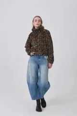 Campera corta de tejido peluche (corderito) con cierre frontal y cuello camisero. Presenta un estampado animal print de cebra o tigre en tonos marrón claro y negro.