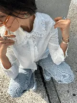 Camisa blanca de lino con cuello babero y detalles de encaje de algodón.