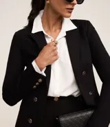 Blazer negro de punto roma con cuello solapa, cierre con ganchos, botones delanteros y forro de poliéster.