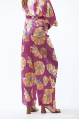 Pantalón de mujer con estampado de flores grandes color naranja sobre fondo fucsia. El pantalón es de corte palazzo y tiro alto.