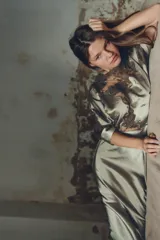 Vestido midi color verde oliva de tejido satinado, con cuello barco, mangas cortas abullonadas con puños y aplicación de encaje a contraste en la parte superior. Cierre trasero con cremallera oculta y botones forrados.