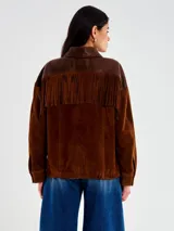 Chaqueta de cuero marrón con diseño western, combinando cuero liso en la parte superior (cuello y tapeta frontal) y gamuza en el cuerpo y mangas. Presenta flecos decorativos en el pecho.