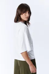 Remera blanca de corte holgado, con cuello alto y mangas 3/4.
