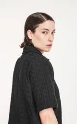 Camisa negra de manga corta con textura y cuello clásico.