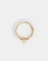 Set de dos pulseras: una con perlas blancas y otra con cadena dorada de eslabones grandes. Cierre con barra en forma de T y dije colgante en forma de lágrima color amarillo pastel.