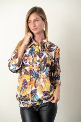 Blusa estampada con hojas en tonos mostaza, verde y blanco. Tiene cuello con lazo, manga tres cuartos y cintura fruncida.