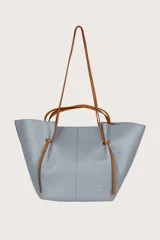 Bolso tote celeste con textura granulada y doble asa, una corta color marrón y otra larga del mismo material.