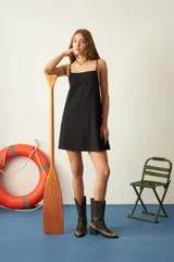 Vestido corto negro con tirantes finos y escote recto. Diseño minimalista y corte recto.