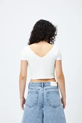 Top blanco de algodón con mezcla de poliéster y elastano, con escote en V delantero y trasero.