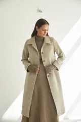 Tapado largo con cuello solapa y corte recto, color gris claro. Tiene cierre frontal con botones ocultos, tajos laterales y bolsillos escondidos en el corte lateral. Está forrado y confeccionado en lana fina sin teñir, diseñada exclusivamente por Don Baez. Hecho 100% en Uruguay.