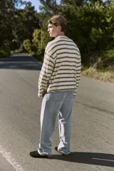 Buzo de manga larga color crudo con rayas horizontales color verde oliva, de corte oversize cropped y cuello redondo.